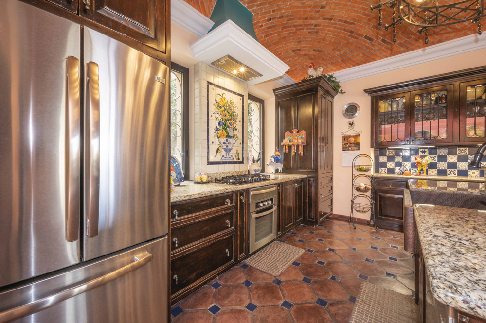 El Obraje main floor, kitchen with refrigerator, oven extractor fan over the stove and tile design on the wall