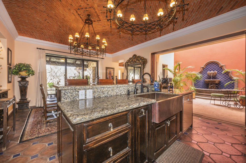 El Obraje main floor, kitchen with marble counters and a small kitchen island with sink and seating, dining area and boveda ceilings plus two handmade iron chandeliers, fountain