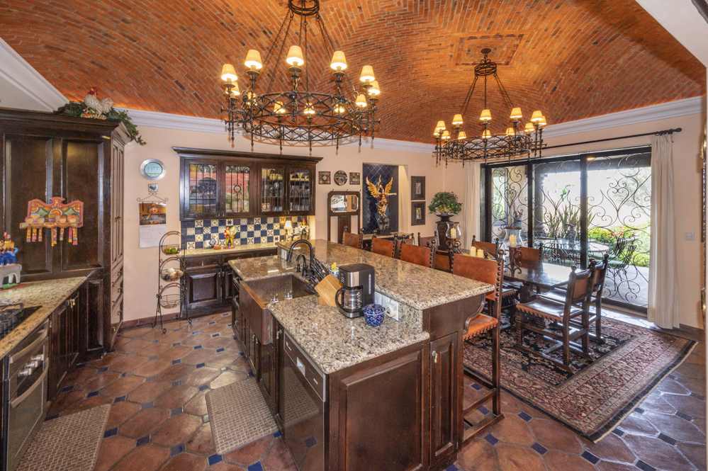 El Obraje main floor, kitchen with marble counters and a small kitchen island with sink and seating, dining area and boveda ceilings plus two handmade iron chandeliers 2